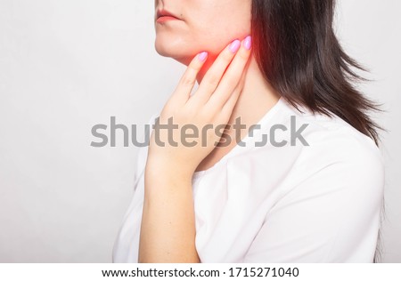 The girl clings to the inflamed salivary gland in which pain. Concept of salivary gland disease, mumps, cancer, copy space Royalty-Free Stock Photo #1715271040