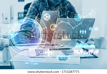 Unrecognizable business people using laptops at blurry table with double exposure of futuristic online work interface. Toned image. Elements of this image furnished by NASA