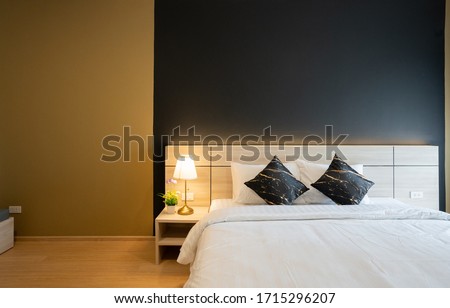 Stylish Bedroom corner with wooden headboard and bed with soft pillows setting with navy blue and yellow painted wall on the background / cozy interior design / modern interior Royalty-Free Stock Photo #1715296207