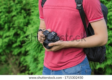 The photographer hold black digital camera in his hands in summer season. Photographer or traveler concept.