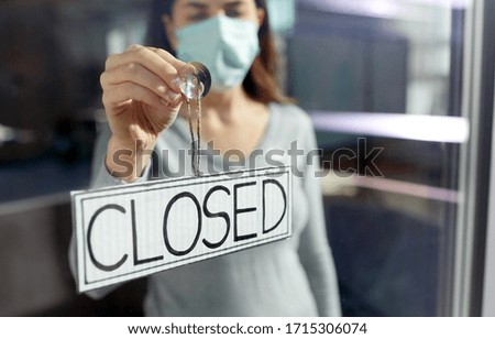 small business, pandemic and service concept - young woman in protective medical face mask hanging banner with closed word on door or window
