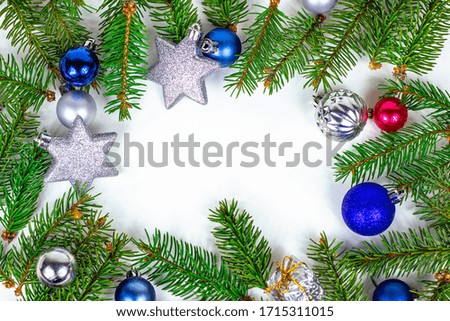 New Year and Christmas frame decoration with copy space, green fir tree branches and blue and silver xmas traditional balls and baubles for greeting invitation cards on white background