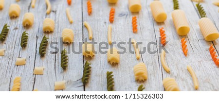 colourful mix of different noodles on wooden background photographed from above
