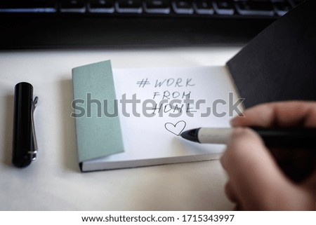 black ink handwriting work from home with a picture of a heart in a notebook on a white background with a keyboard and pen in connection with the coronavirus