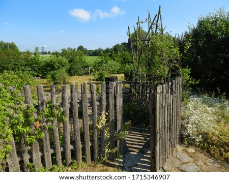 Entrance to the vegetable and flower garden. A hand-made wooden fence. The garden is surrounded by an old fence in the countryside. 