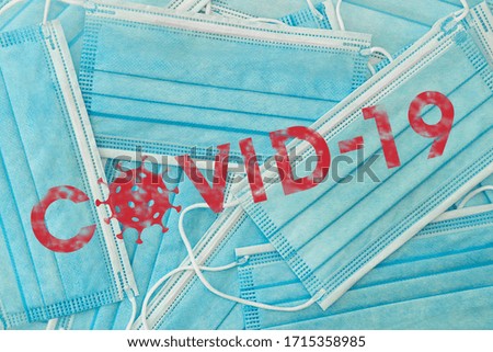 Covid-19 text lettering in red with grunge effect and coronavirus icon on surgical blue medical masks background photo.