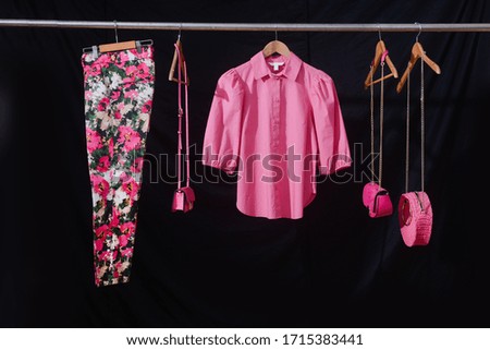 Fashion woman pink blouse clothes and floral pattern pants and three handbag on black background
