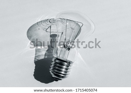 Old incandescent light bulb with a sharp shadow. Minimalistic black and white photo. The concept of development and energy conservation