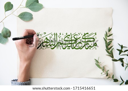Ramadan Kareem Islamic design in Arabic calligraphy font writing by hand with leaves background.