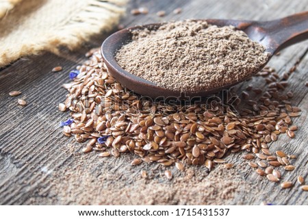 Crushed flax seed in a wooden spoon on a pile of flaxseed. Ground seed is used to prevent heart disease and being overweight. Royalty-Free Stock Photo #1715431537