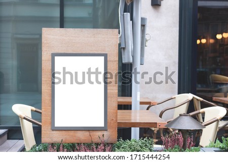 Blank signboard at sidewalk with outdoor chairs and table