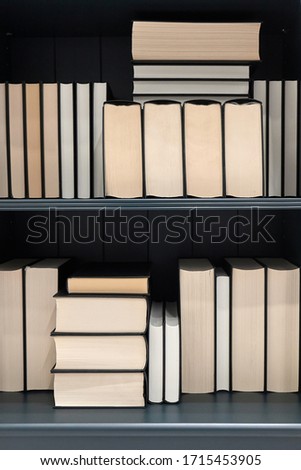 Bookshelf with series of books in piles and rows