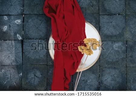 red cloth on wood texture with dried plant. Top view. 
rustik style.