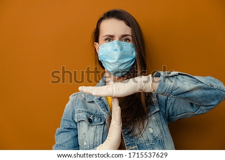 Portrait of dissatisfied woman in medical sterile face mask gloves, shows timeout gesture, needs stop, isolated over on brown wall. Epidemic pandemic spreading coronavirus 2019-ncov, flu virus concept