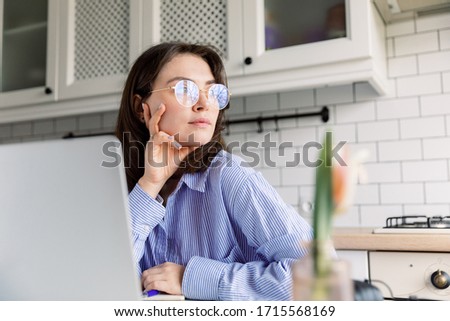 Cheerful young woman using laptop sit home in kitchen. Blogger, writer, journalist, student girl working on computer at home. Businesswoman, work from home, distance education, online learning