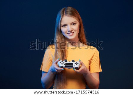 Gamer girl. Smiling girl holding video game joystick on blue background