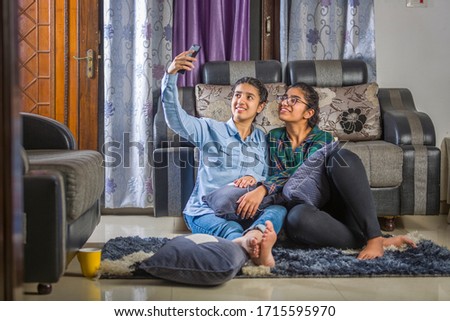 two girls sitting at home taking selfie and having fun