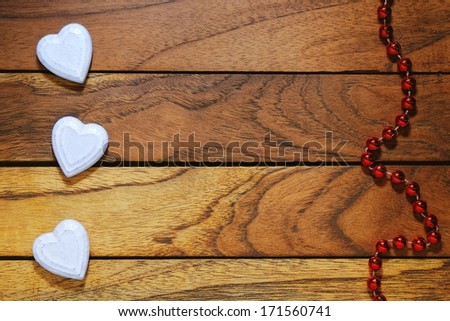 three white hearts misaligned with wood background with necklace