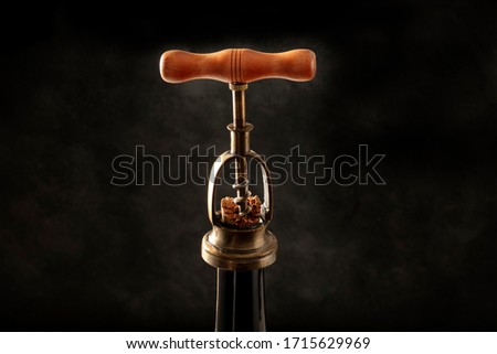 Wine design template. A vintage corkscrew, pulling out a cork from a bottle on a black background