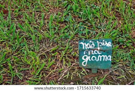 Sign board on the public square asking do not step on the grass, in portuguese language                              