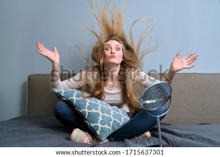 Funny young blond woman with long hair having fun sitting in bed, waving her head and hands, in photo moment with her hair raised up. Youth, fun, happiness, holiday young people concept