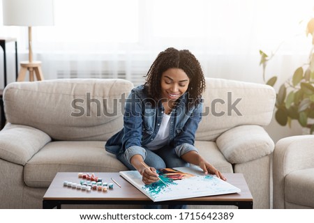 Painting For Beginners. Young black woman drawing picture by numbers with acrylic paints on canvas, enjoying creative leisure activities