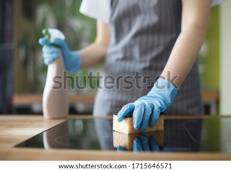 Quarantine cleaning. Unrecognizable woman cleaning kitchen in gloves with disinfecting spray, blurred background