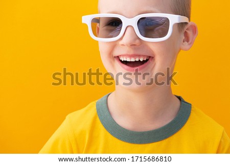 Cheerful baby boy with white 3d movie glasses on a yellow background