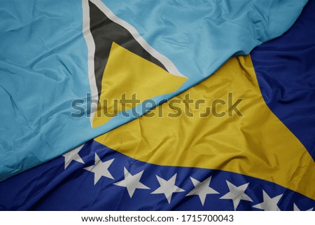 waving colorful flag of bosnia and herzegovina and national flag of saint lucia. macro