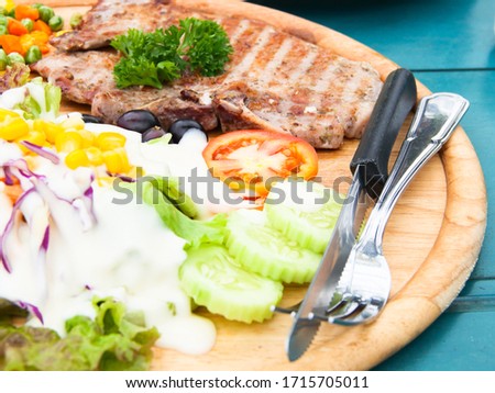 Picture of a half steak, complete with a salad, spoon, and knife.Soft focus.