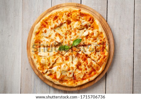 Tasty hawaiian pizza with chicken and pineapple on wooden cutting board. Top view Royalty-Free Stock Photo #1715706736