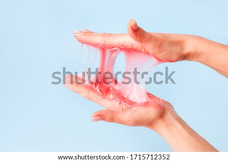 Young girl hands with sticky purple slime on blue background, liquid wax for depilation, conceptual flyer banner with copy space, antistress relax, modern kids hobby oddly satisfying semi surreal asmr Royalty-Free Stock Photo #1715712352
