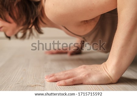 Woman doing push-ups exercise on hands or practicing yoga at home. Close-up of hands. Body positive trend.