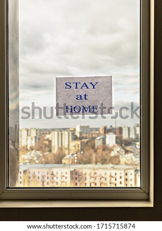 Window with a view of the city and the inscription in English "STAY AT HOME". The importance of staying in isolation at home to prevent coronavirus infection.Pandemic COVID-19