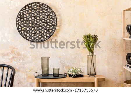 Interior design of living room with stylish black chair, wooden console, books, plant, flower in vase, decoration, grunge wall and elegant personal accessories in modern home decor.