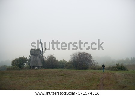 Mill in fog. Lonely person in the field. Russia.