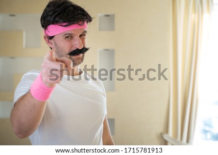 Funny man with a mustache points a finger at the camera