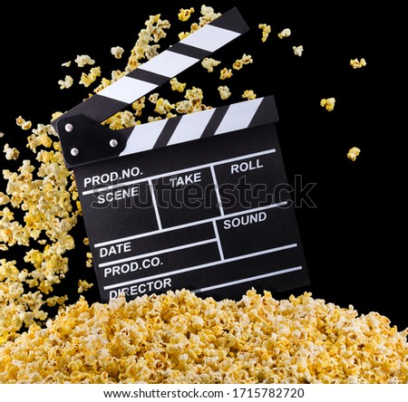 Flying popcorn and film clapper board isolated on black background, concept of watching TV or cinema.