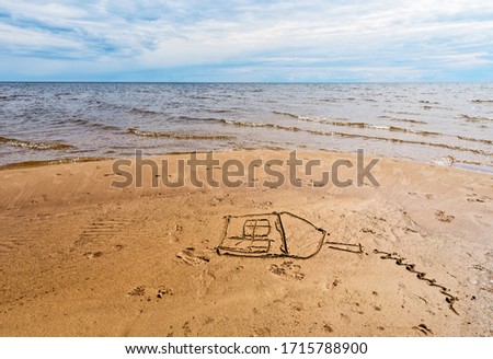 A child has drawn a house on reddish beach sand.