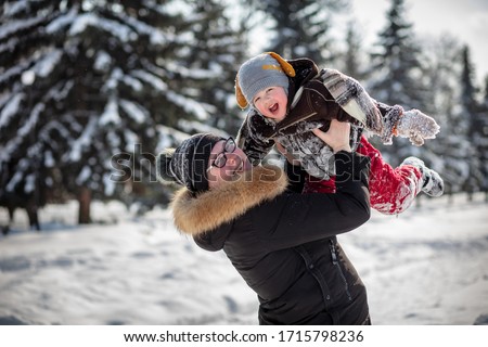 Mother holds her baby in her arms. Beautiful winter. Christmas trees in the snow in the background. The game in the snow.