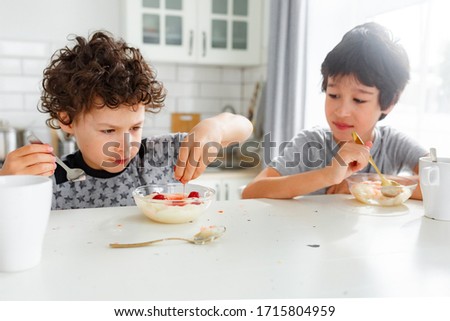 real brothers have breakfast in the morning in a bright Scandinavian style kitchen with porridge with strawberries