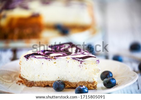 A slice of delicious homemade blueberry marble cheesecake with graham cracker crust and fresh berries. Selective focus with extreme shallow depth of field.