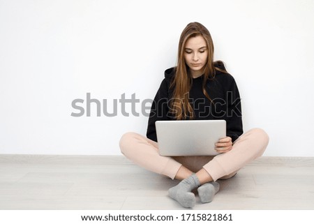Smiling freelancer girl woman in sweater sitting on the floor with laptop computer, concept online education, work from home, on white background, copy space