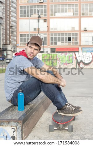 Skateboarder sitting in the park with skate and bottle of energy