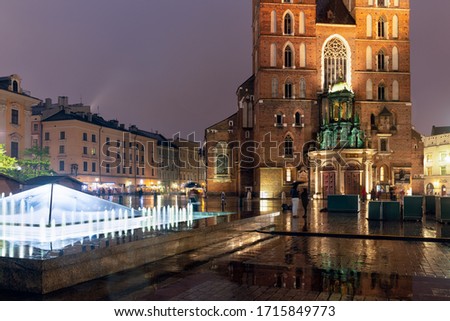 Rainy evening view main market square Polish Krakow with St. Marys Church and fountain