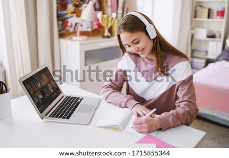 Young female student sitting at the table, using laptop when studying.