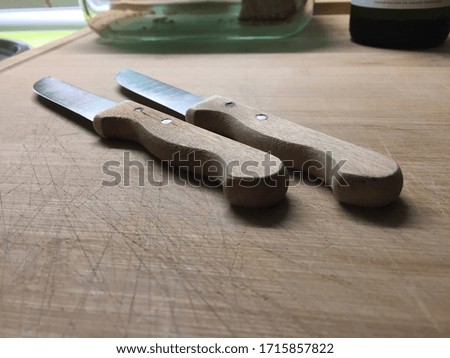 Two knives over a wooden cutting board