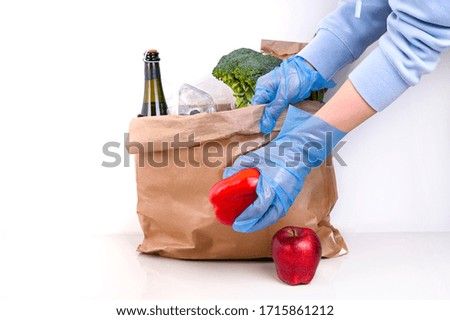 A person with a set of food in hand on white background. Paper bag with Food supplies crisis food stock for quarantine isolation period. Food delivery, Donation, coronavirus. Soft focus. Copy space.