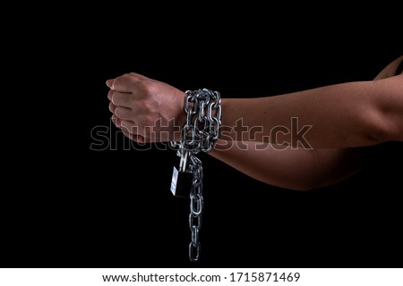 Woman hand tied up with steel chain and lock at the black background, Human rights violations and International women's Day concept, Front view women