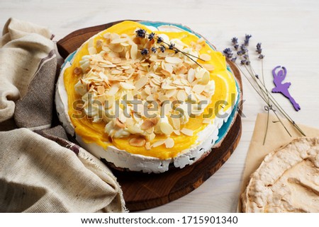 Pavlova dessert with meringue, lemon cream, cream cheese and almond flakes on a white background